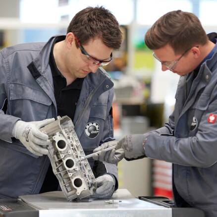 Zwei Mitarbeiter prüfen ein Motorbestandteil