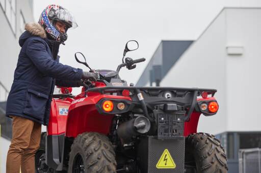 Mitarbeiter mit Helm steht neben einem roten CanAm